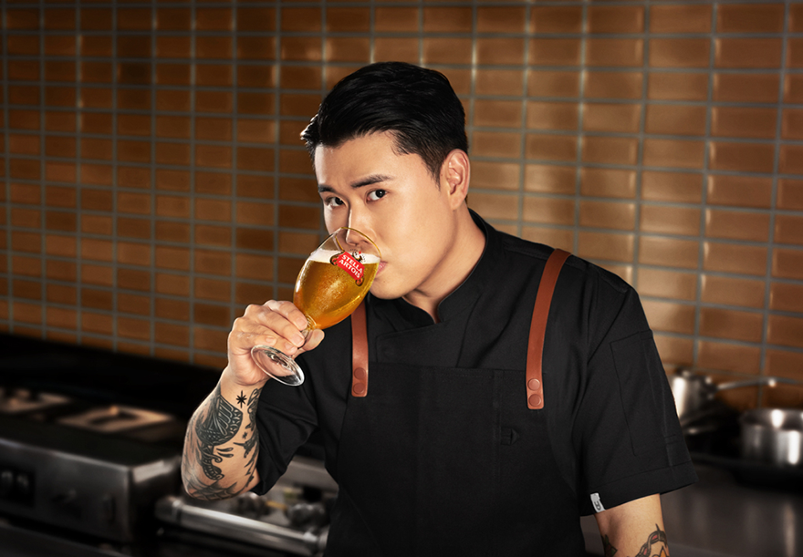 스텔라 아르투아 x 권성준 셰프의 만남 권성동 쉐프가 스텔라 아르투아 생맥주가 가득찬 전용잔인 챌리스 잔을 들고 마시면서 카메라를 응시하고 있습니다